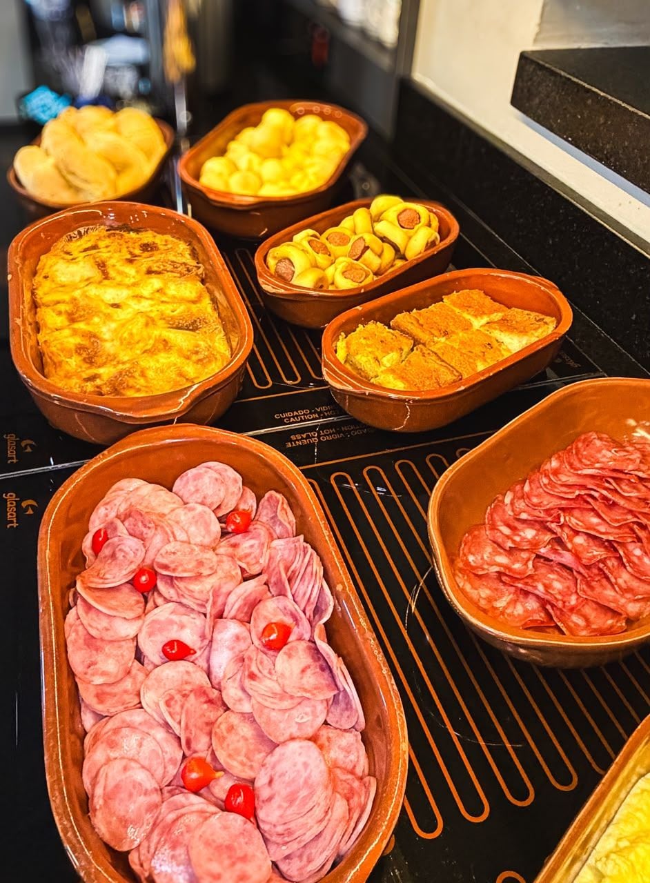 A buffet with various dishes including a casserole, sliced sausages, and a dish with yellow items.