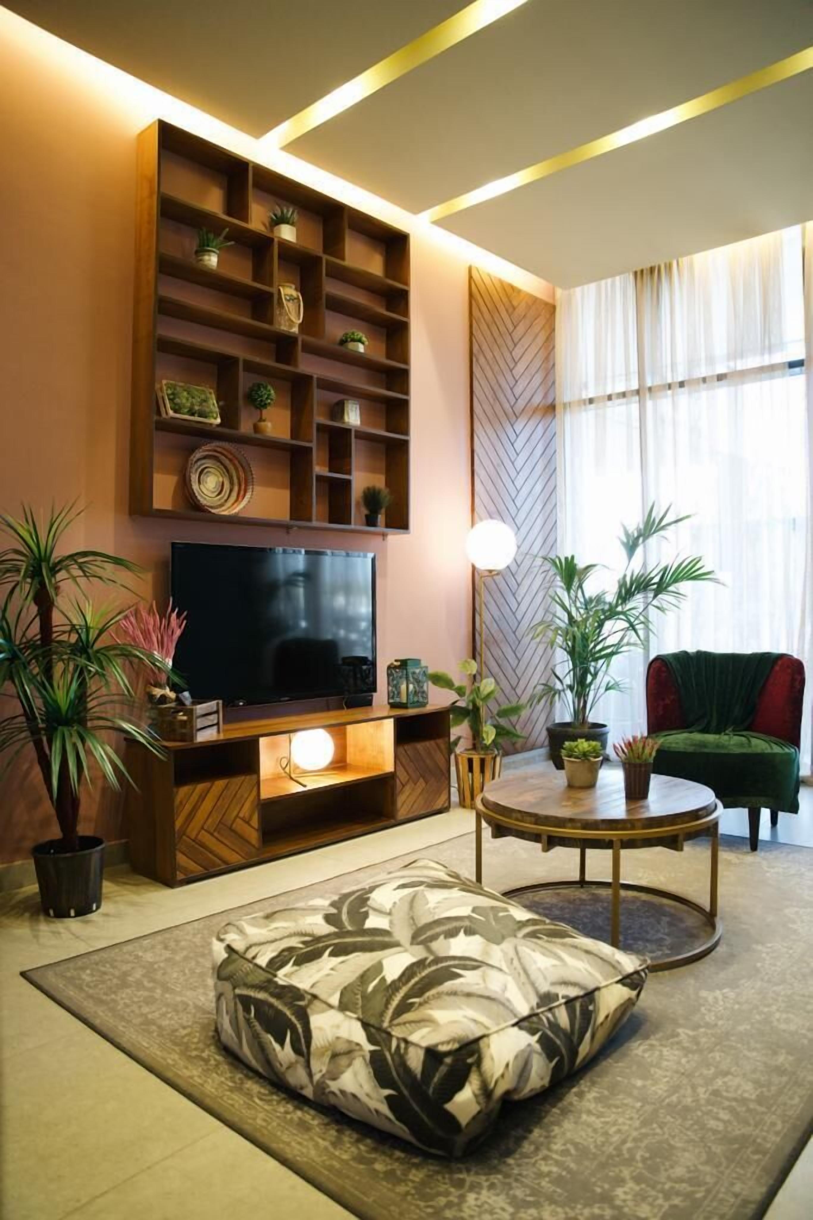 Ein Wohnzimmer mit Fernseher, Holzregalen, einem runden Couchtisch und einem grünen Sofa.