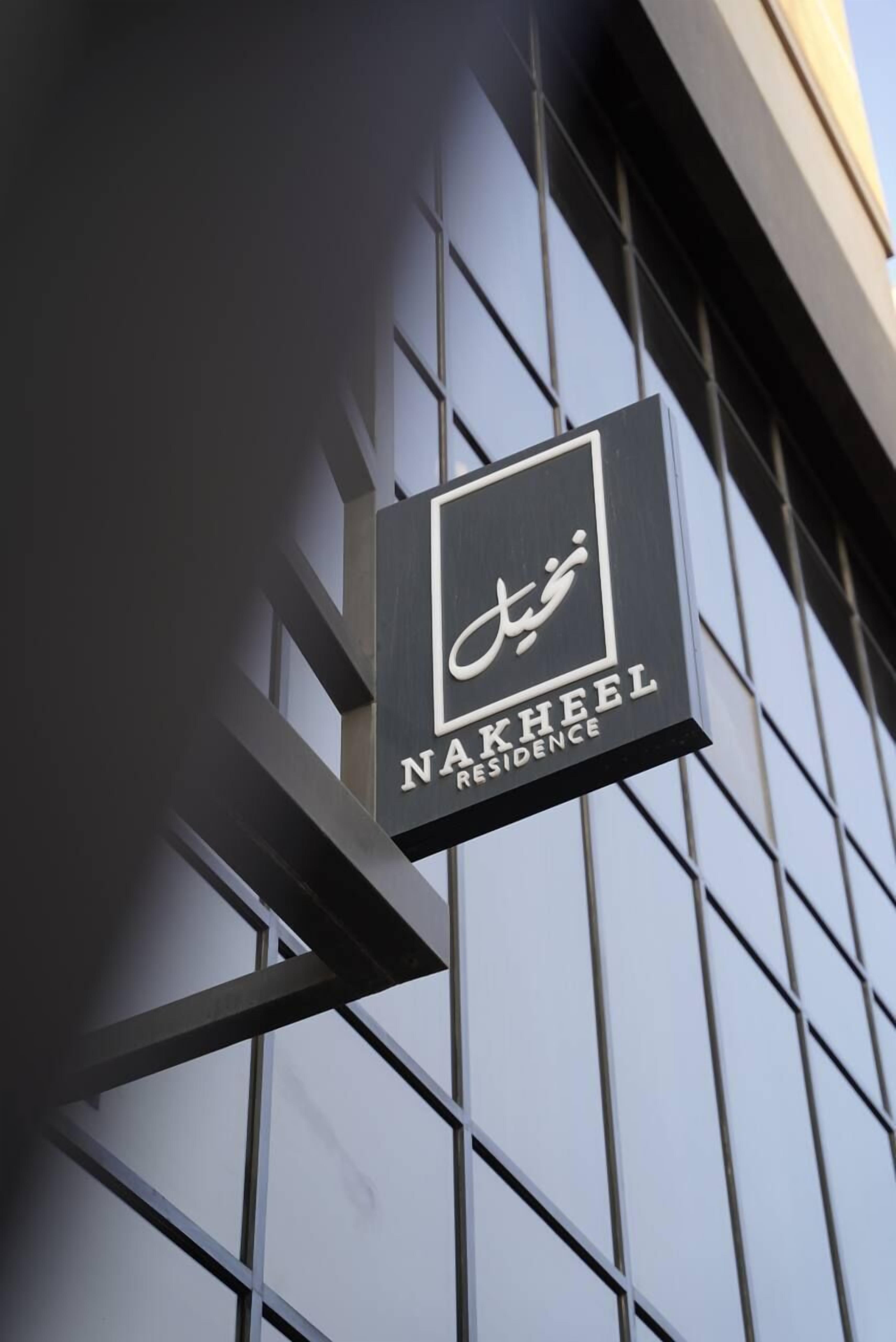 Une enseigne pour le Nakheel Residence, avec une architecture moderne en arrière-plan.