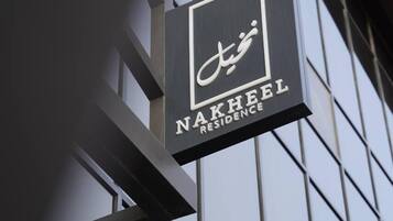 A sign for Nakheel Residence with a modern architectural background.