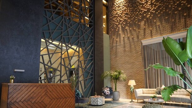 A modern lobby with a wooden reception desk, a geometric wall design, a brick wall, a sofa, and a large plant. - Nakheel Residence by House living (Sabah Al Salem)
