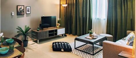 Una sala de estar moderna con un televisor de pantalla plana, una mesa de centro, un sofá y un comedor con una mesa y sillas.