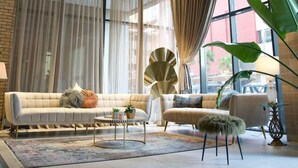 A spacious living room with a brick wall, large windows, and modern furniture. - Nakheel Residence by House living (Sabah Al Salem)