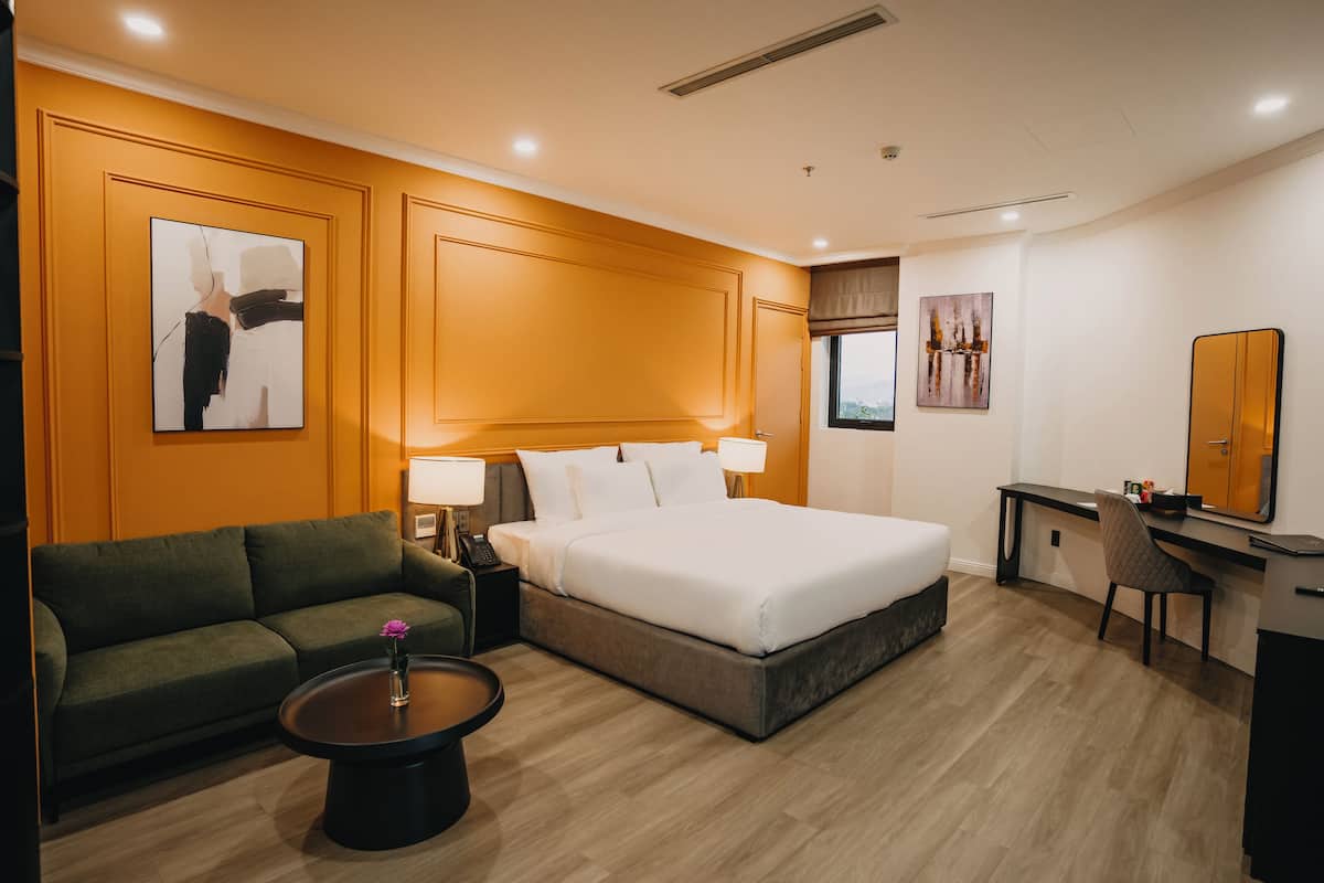 Una habitación de hotel con una cama, un sofá, un escritorio y una silla.