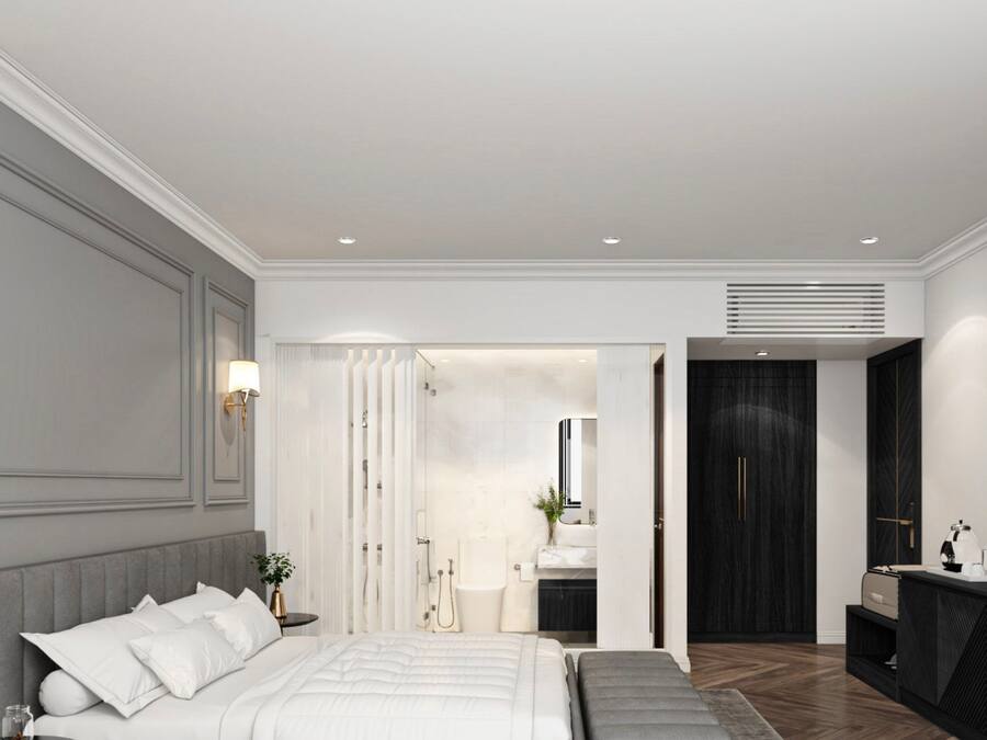 A modern bedroom with a large bed, a bedside table, a mirror, a dark wardrobe, and a bathroom visible through an open door.