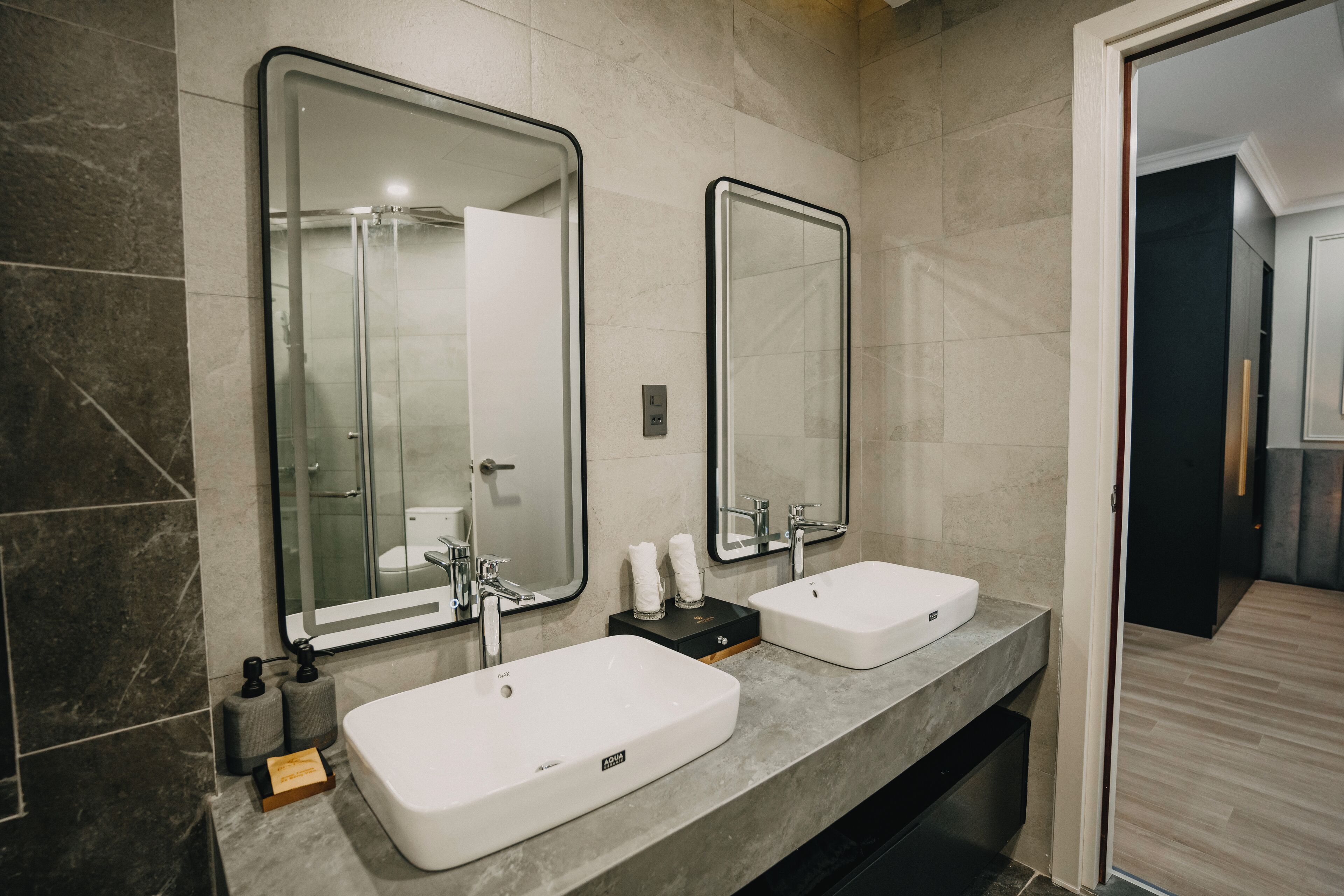 Un baño moderno con dos lavamanos, espejos grandes y una ducha.