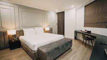 A modern hotel room with a large bed, bedside lamps, a desk, and a chair.