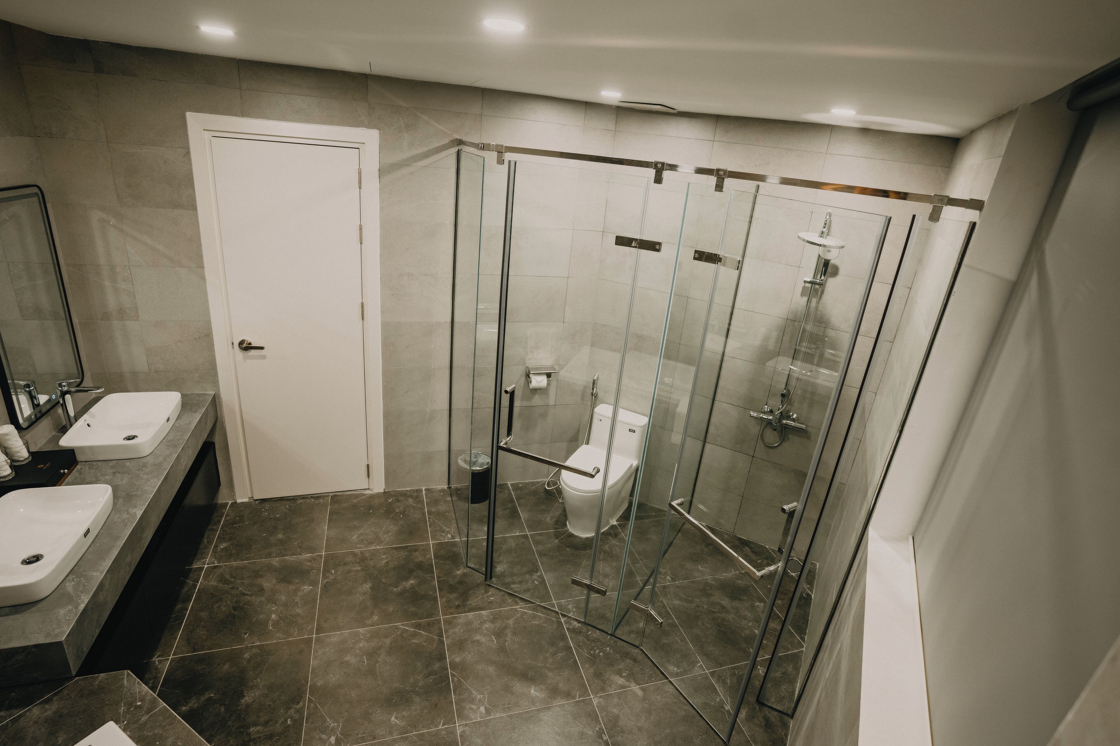 A modern bathroom with two sinks, a toilet, and a glass-enclosed shower area.