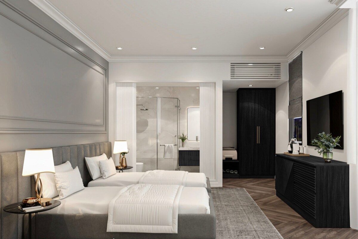 A modern bedroom with a large bed, bedside tables, a walk-in closet, and a bathroom with a shower.