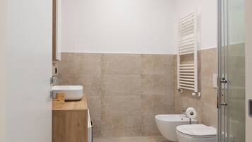 A modern bathroom with a wooden vanity, a glass shower enclosure, and a white sink.