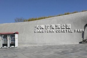 Un grand mur en béton sur lequel est inscrit le texte « Dameisha Coastal Park » en chinois et en anglais.