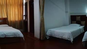 Quarto de hotel com duas camas, piso de madeira e cortina na janela.