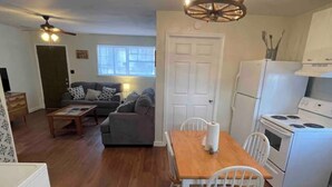 Un espacio habitable compacto con comedor, kitchenette y zona de estar con sofá y mesa de centro.