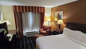 Une chambre d’hôtel avec un lit, un bureau équipé d’un ordinateur, une chaise, une lampe et un tableau au mur.