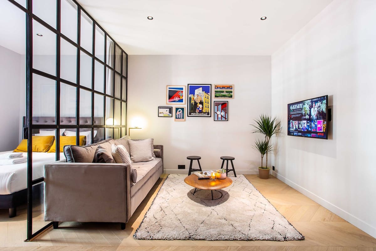 A modern living room with a sofa, a coffee table, and a TV mounted on the wall.