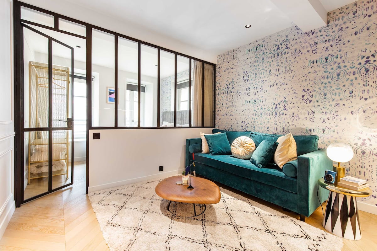 A modern living room with a teal sofa, patterned rug, and a coffee table.