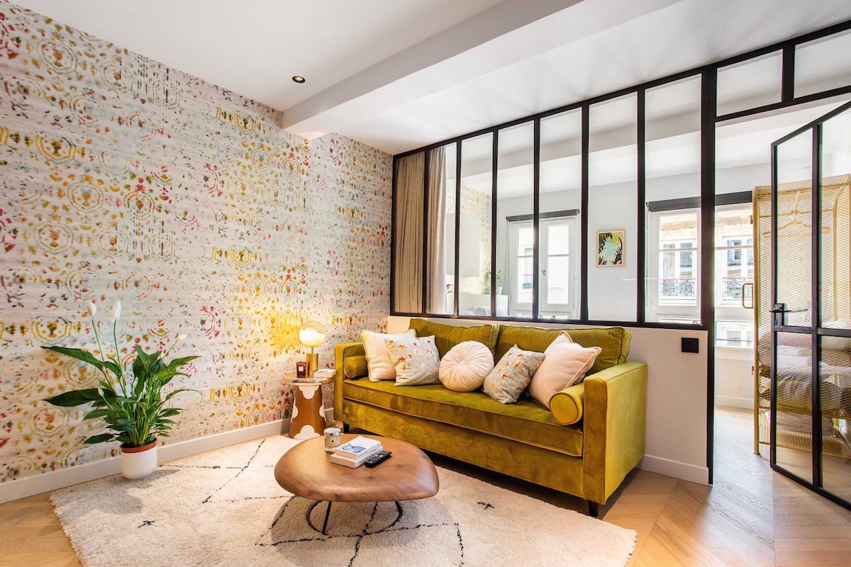 A modern living room with a green sofa, a coffee table, and a potted plant.