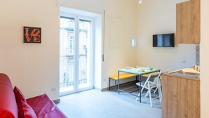 Eine moderne Wohnung mit einem roten Sofa, einem Essbereich, einer Küche und einem großen Fenster.
