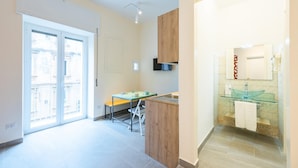 Eine moderne Küche mit einer Holzecke, einem Essbereich mit einer Bank und einem Badezimmer mit Waschbecken aus Glas und Spiegel.