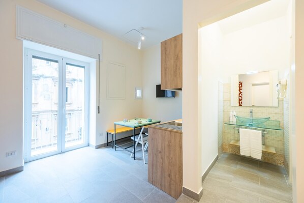 Eine moderne Küche mit einer Holzecke, einem Essbereich mit einer Bank und einem Badezimmer mit Waschbecken aus Glas und Spiegel.