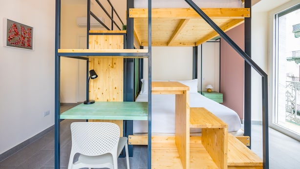 Une petite pièce comprenant un lit superposé, un bureau et une chaise.