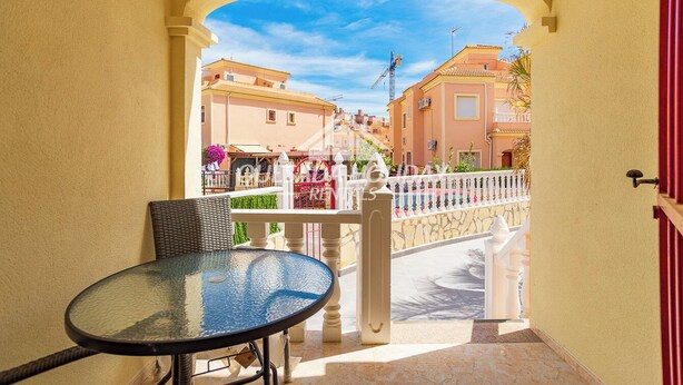 A glass table and chair in a sunlit balcony with a view of a street and buildings. - Villa La Zenia close to Beach, private pool, walking distance of Zenia Boulevard (Orihuela)