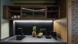 A modern kitchen with a built-in sink, a fruit bowl with bananas and a pineapple, and a microwave. - Epineio Comfort Living (Dio-Olympos)