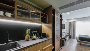 A modern kitchen with wooden cabinets, a black countertop, and a sink. There is a fruit bowl with bananas and a pineapple on the counter. - Epineio Comfort Living (Dio-Olympos)