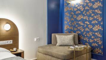 Un dormitorio moderno con una cama, un pequeño sofá y una pared con estampado floral azul.
