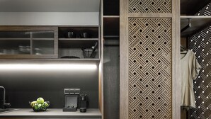 A modern kitchen with wooden cabinets, a built-in coffee maker, and a patterned divider. - Epineio Comfort Living (Dio-Olympos)