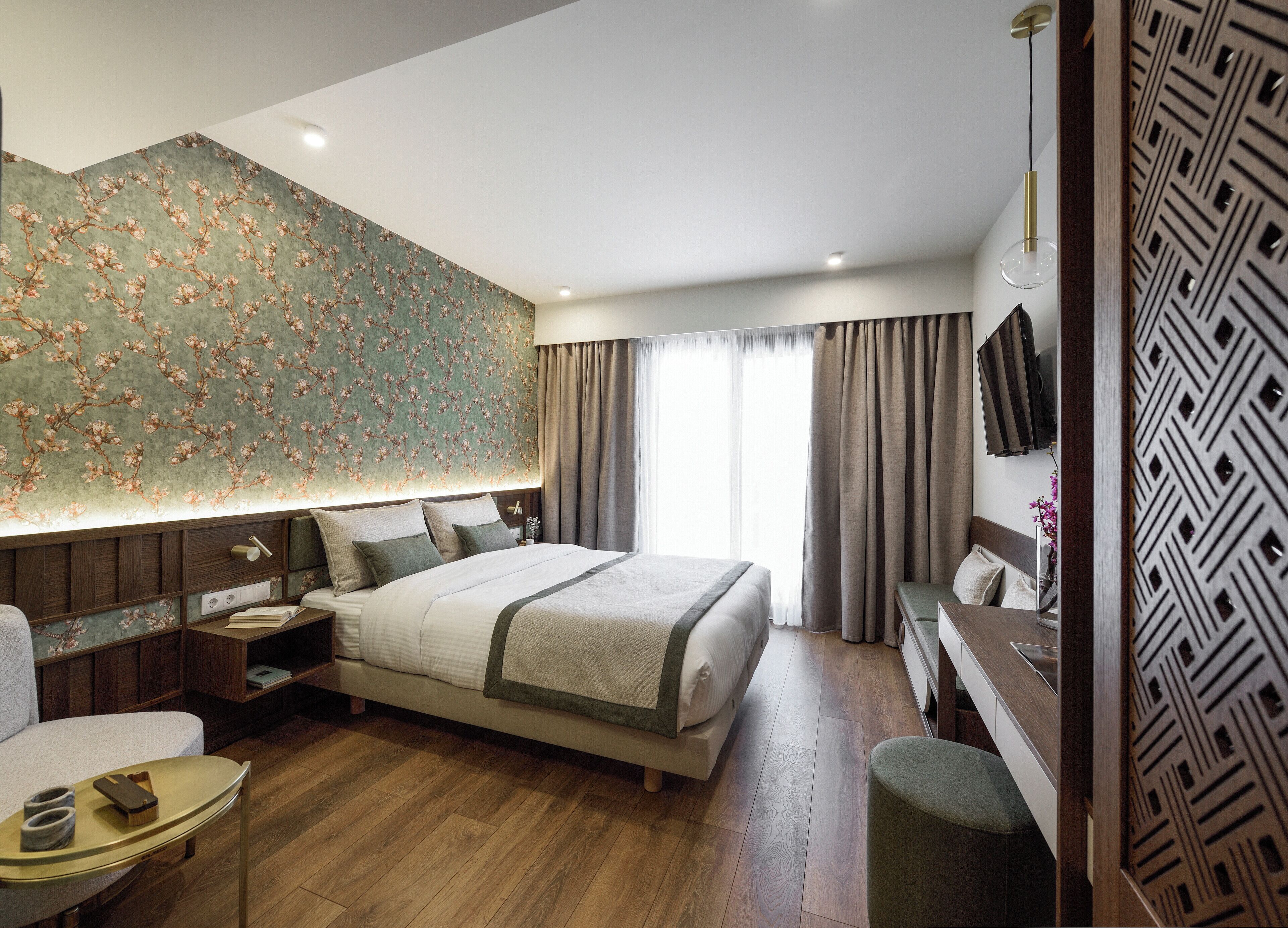 Una habitación de hotel moderna con una cama grande, un escritorio, una silla y un televisor montado en la pared.