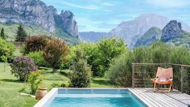 A pool area with a wooden deck, a lounge chair, and a mountainous landscape in the background. - Pomerolle - Saoû - 4 pers (Saou)
