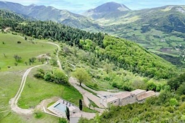 Un paysage rural avec un petit bâtiment, un sentier sinueux et un espace piscine.