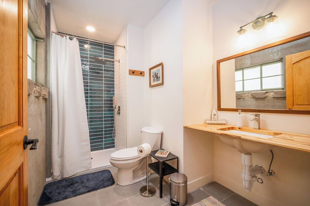 Un baño con inodoro, lavamanos y zona de ducha.