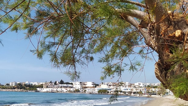 A beach with footprints, a rocky cliff, and buildings in the background. - Sea View And Mountain View Apartment For 4 People (Ierapetra)