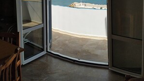 An open sliding door leading to a balcony with a view of a beach and distant mountains. - Sea View And Mountain View Apartment For 4 People (Ierapetra)