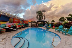 Una piscina con area relax, una zona con posti a sedere coperta e un murale colorato sull'edificio.