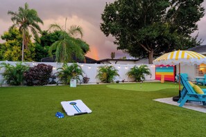 Um quintal com gramado, balanço e uma casinha de brincar colorida.