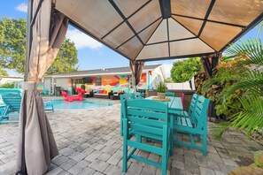 A covered outdoor area with a pool, seating, and a building with colorful murals.