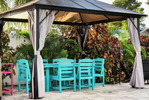 Un gazebo con tavolo e sedie, immerso nel verde.