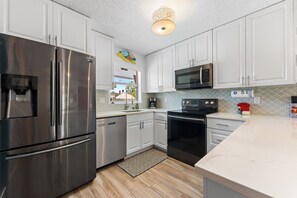 A modern kitchen with stainless steel appliances, white cabinetry, and a patterned backsplash.