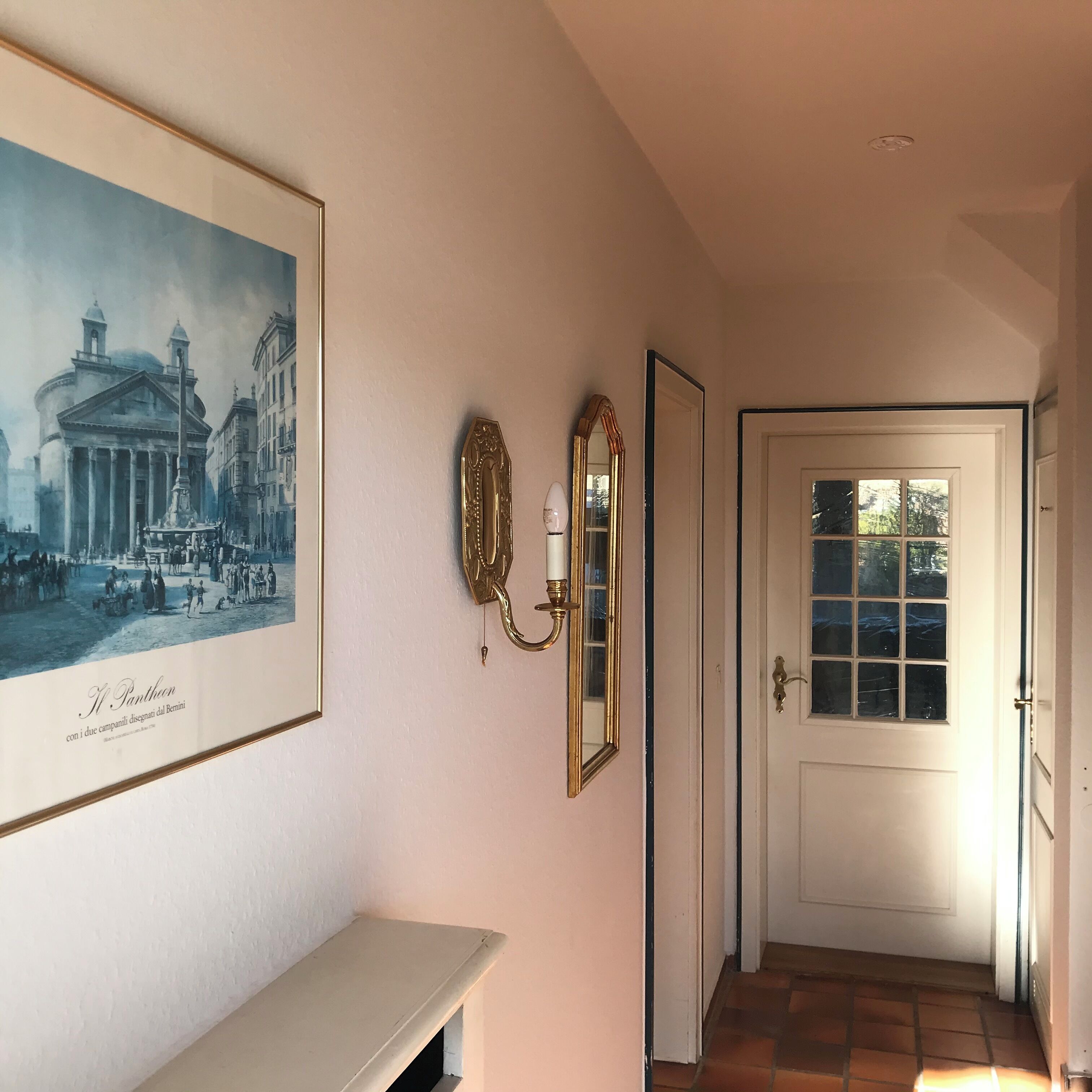 Un corridoio con un quadro storico incorniciato, due specchi a parete e una porta che dà su un'altra stanza.