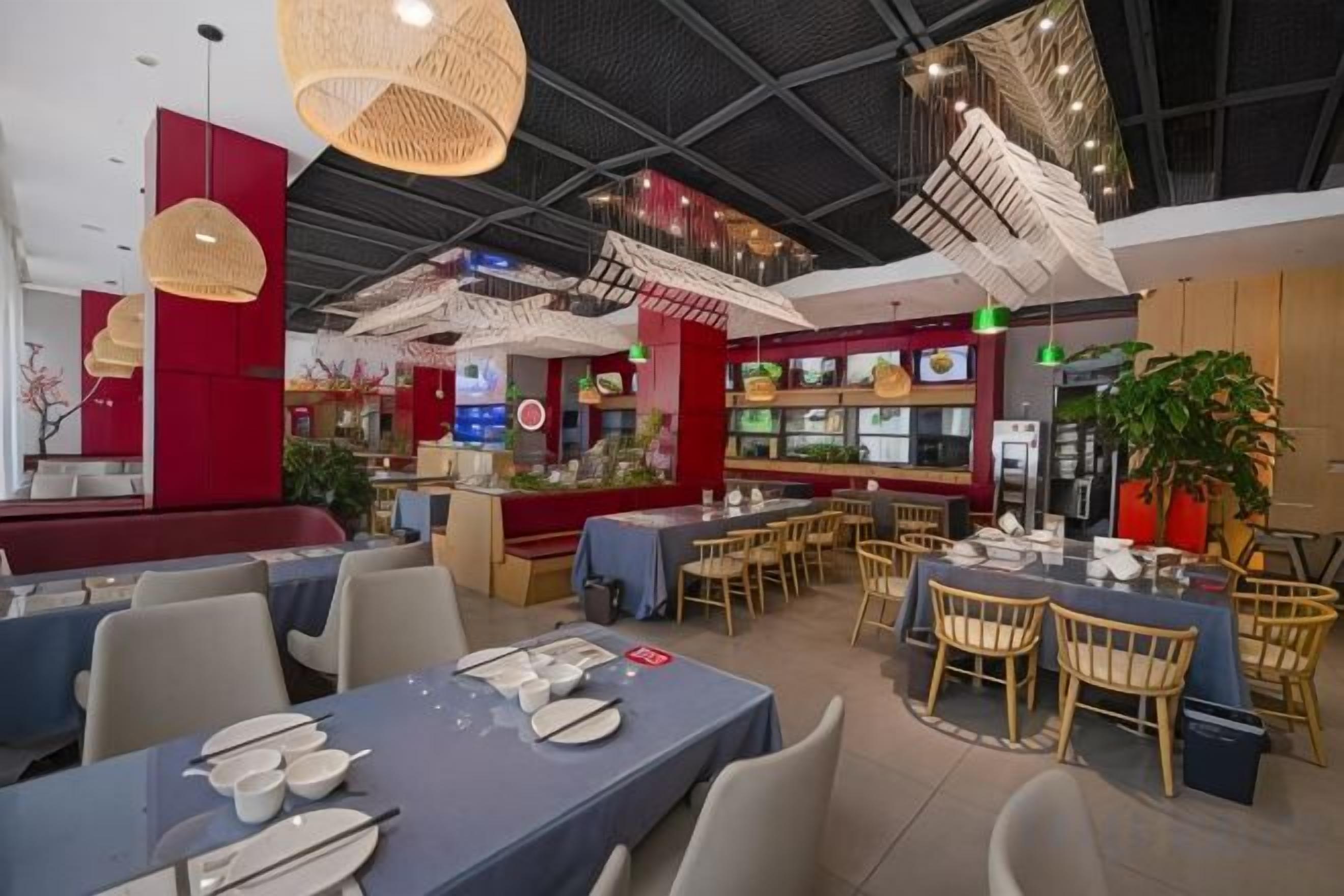 Un restaurante con varias mesas y sillas, una barra con menú y lámparas colgantes.