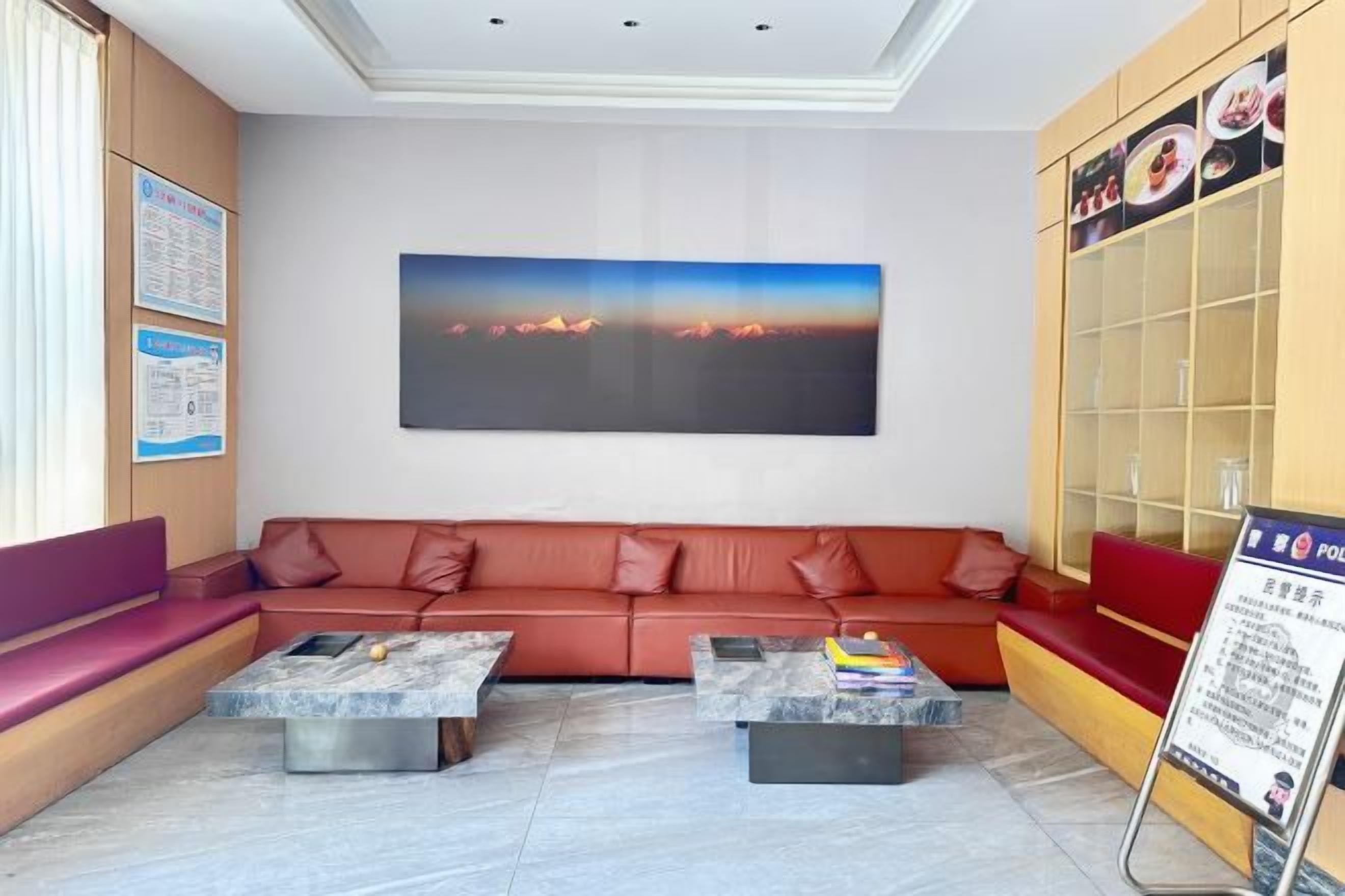 A modern lobby with a red sofa, two marble coffee tables, a large abstract painting, and a glass display cabinet.