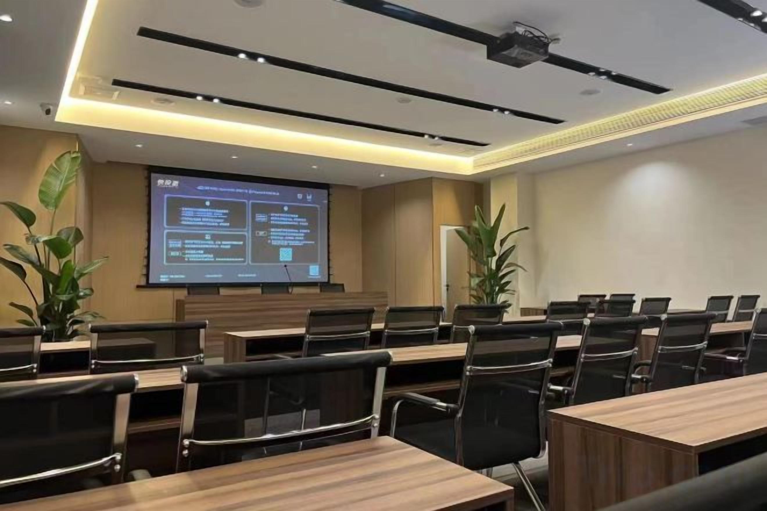A conference room with a large screen displaying a presentation, multiple tables, and chairs arranged for meetings.
