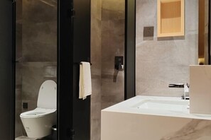 Une salle de bain moderne équipée de toilettes, d’un lavabo et d’un miroir.