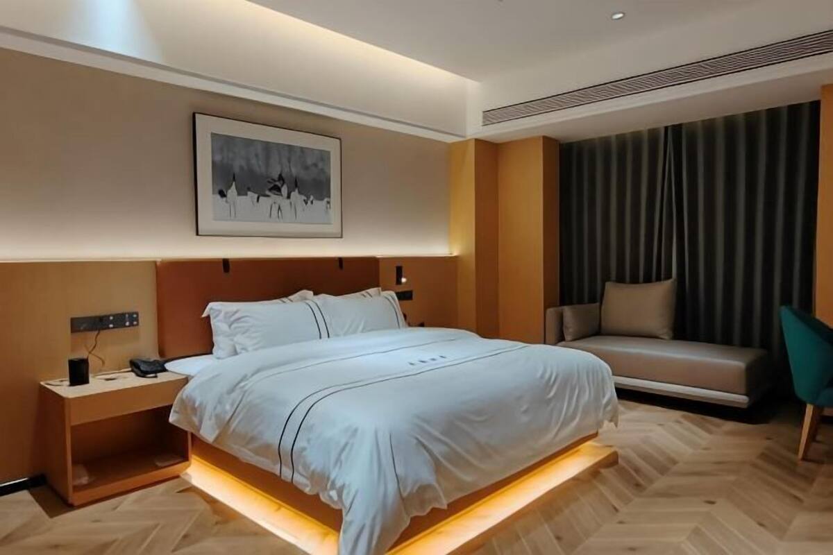 Una habitación de hotel moderna con una cama grande, una mesita de noche y un sofá.