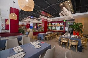 A restaurant with tables and chairs, a counter, and hanging lights. - Mianzhu Youdao Club Hotel (Mianzhu)