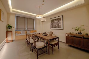 A dining area with a wooden table and chairs, a bench, a hanging light fixture, and a framed picture on the wall. - Mianzhu Youdao Club Hotel (Mianzhu)