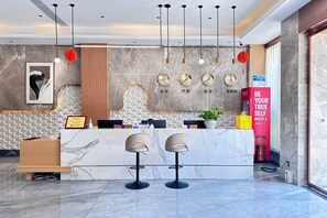 A hotel reception area with a marble counter, two bar stools, a clock, and a red sign. - Mianzhu Youdao Club Hotel (Mianzhu)